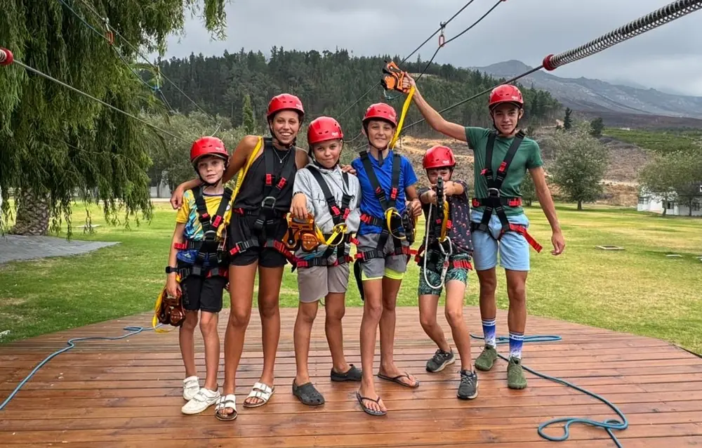 A group of children in red helmets and harnesses on the Houw Hoek Zipline launch deck