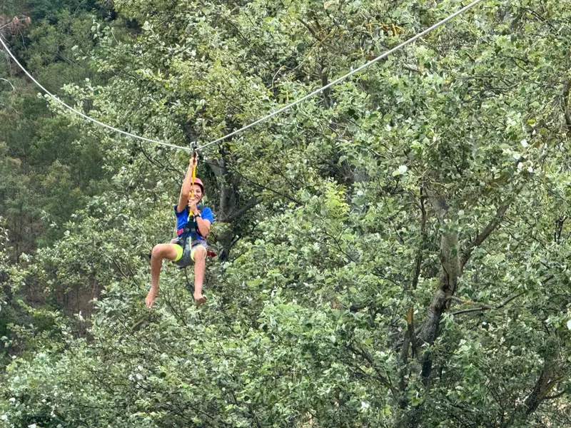 A rider gliding through green treetops on the Houw Hoek Zipline