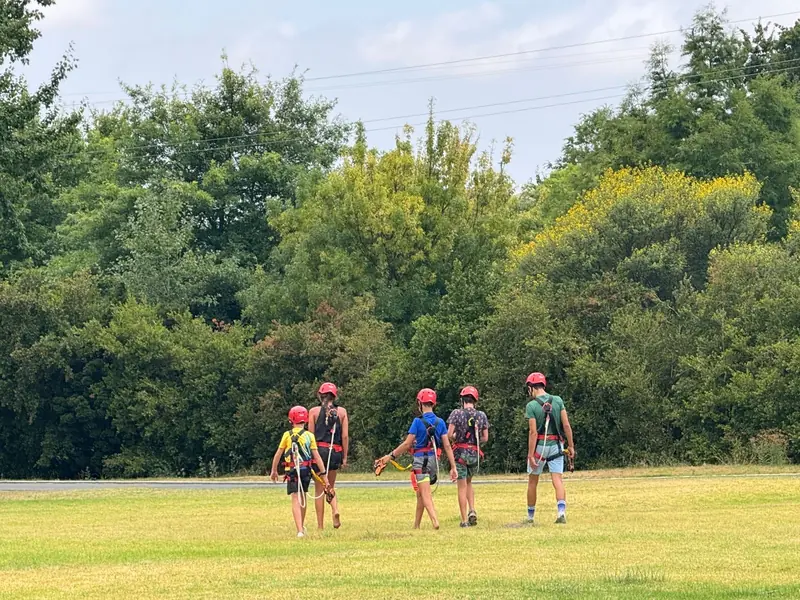 Children in harnesses walking back across the lawn after riding the Houw Hoek Zipline